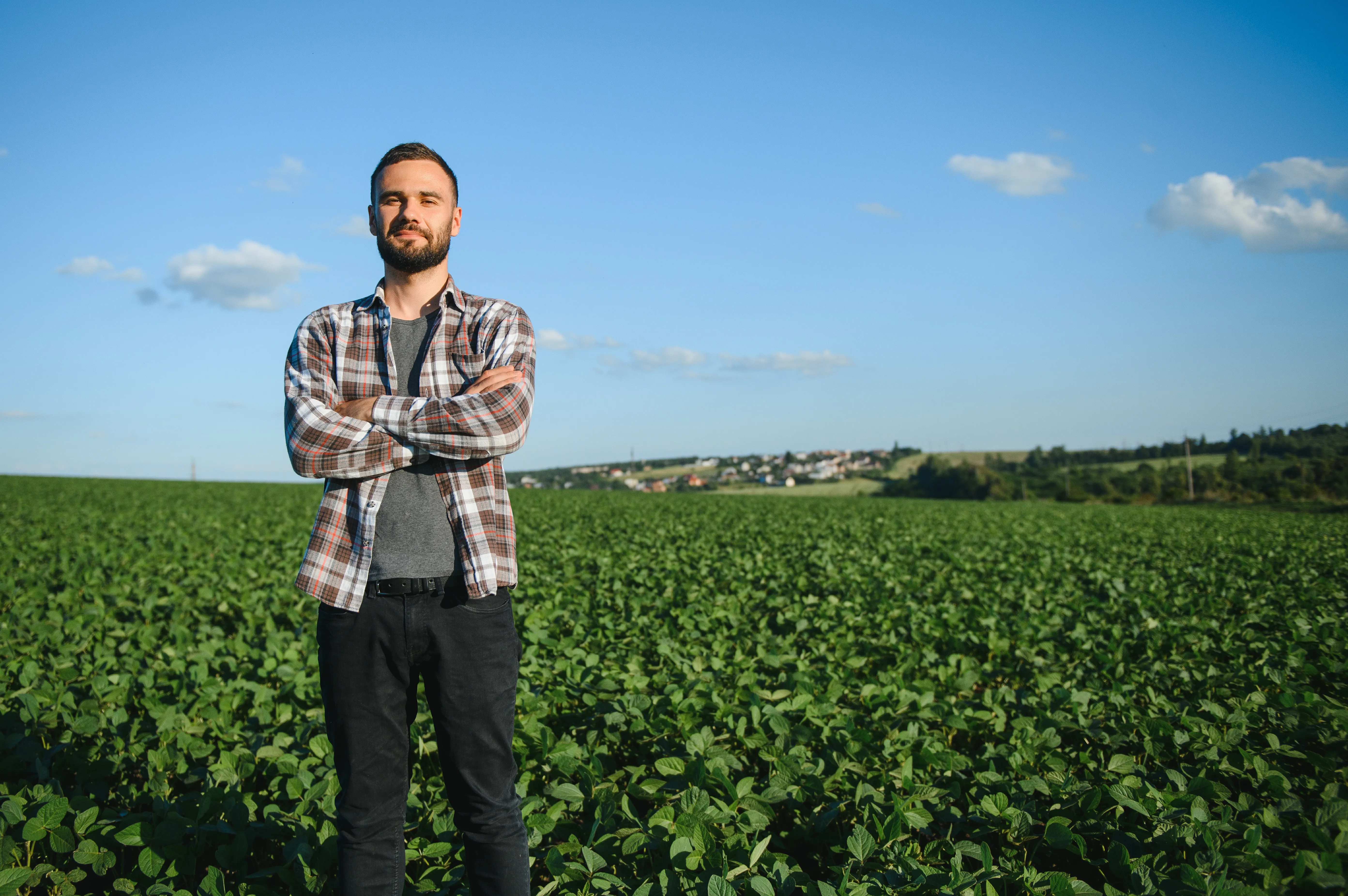 Rapaz em pé com os braços cruzados em um campo verde