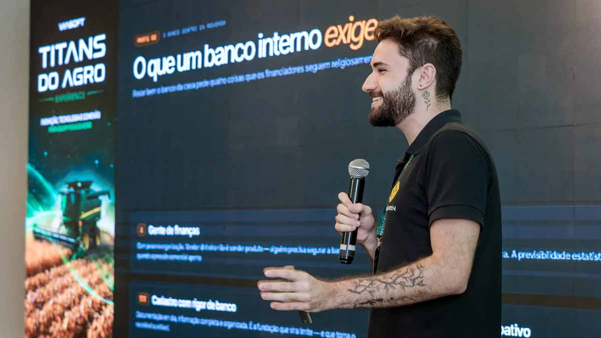Palestrante ao microfone diante de um slide com o título O que um banco interno exige