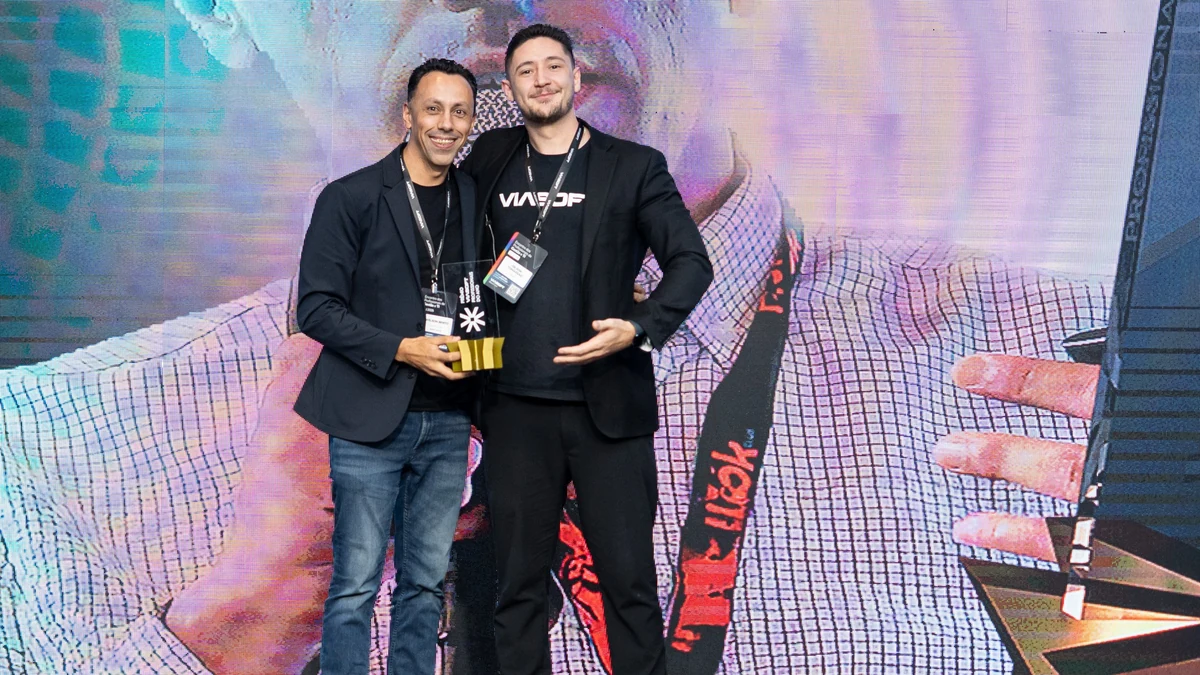 Wilson Bento segura o troféu do Prêmio VIASOFT Profissionais do Ano ao lado de Gilson Tomassão, no palco do Encontro de Profissionais 2025